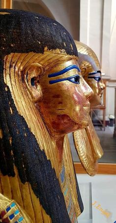 three golden statues of egyptian pharaohs with blue eyes and gold headdress on display