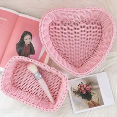 two pink heart shaped baskets sitting on top of a white fur covered floor next to an open magazine