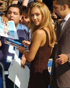 a woman in a brown dress signing autographs for fans