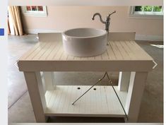 a white sink sitting on top of a wooden table next to a metal faucet