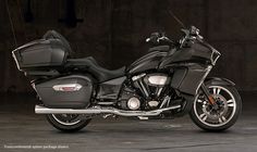 a black motorcycle parked in a garage next to a cement wall and flooring area