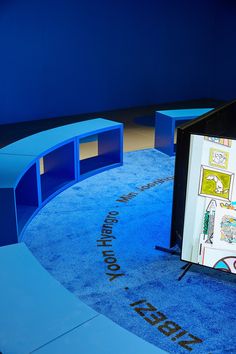 a blue carpeted room with an open book case on the floor and writing on the wall