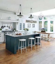 a kitchen with white cabinets and green island in the center, surrounded by stools