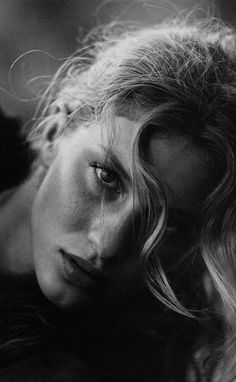 a black and white photo of a woman with her hair blowing in the wind,