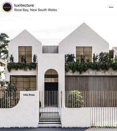 an image of a white house with plants growing on the wall and stairs leading up to it