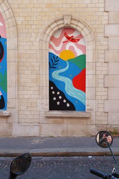 a motorcycle parked in front of a building with two paintings on it's side