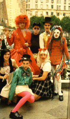 a group of people dressed up in costume posing for a photo with clowns on the street