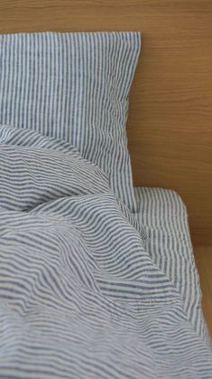 an unmade bed with blue and white striped sheets