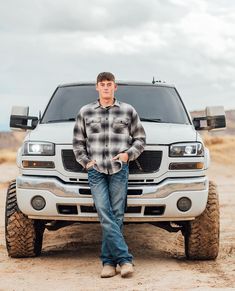 a man standing in front of a white truck with his hands on his hips and looking at the camera