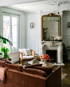 a living room filled with furniture and a fire place in front of a mirror on the wall