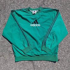 Staying true to my wife's era is this, 90s style fit that all the coolest of kids rocked! Cop this gorgeous vintage Adidas pullover windbreaker sporting the black racer stripe sleeve half-side zip sized as a large in the color green. Please, before my wife decides to keep it. Haha. Sporty Track Jacket With Three Stripes And Crew Neck, Crew Neck Outerwear With Three Stripes For Streetwear, Three Stripes Windbreaker For Streetwear, Sporty Crew Neck Track Jacket For Streetwear, Three Stripes Long Sleeve Track Jacket For Outdoor Activities, Sportswear Windbreaker With Three Stripes, Green Streetwear Tops With Three Stripes, Green Three Stripes Tops For Streetwear, Long Sleeve Windbreaker With Three Stripes