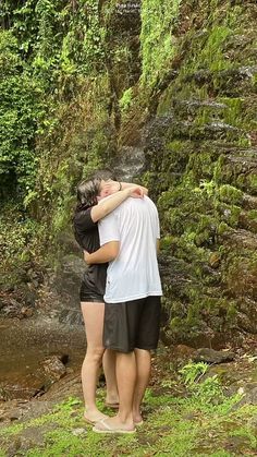 a man and woman standing in front of a waterfall with their arms around each other