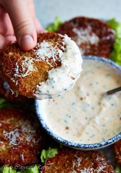 a person dipping some kind of food into a bowl with ranch dressing on the side