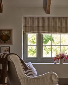 a living room filled with furniture and a window covered in roman blind shades on the windowsill