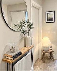 a mirror on the wall above a radiator in a room with white walls and wood flooring