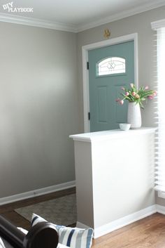 a room with a blue door and some flowers in a vase on the front desk