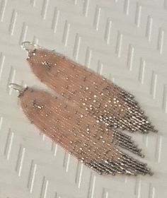 a pair of silver and gold earrings sitting on top of a piece of white paper