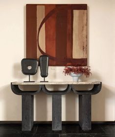 two black vases sitting on top of a wooden table in front of a painting