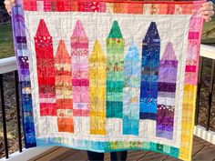 a person holding up a quilt made with crayons on the front and back