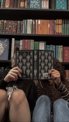 a person sitting on a couch in front of a bookshelf with many books