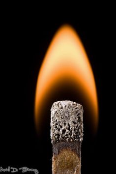 a matchstick is lit with orange flames in the background