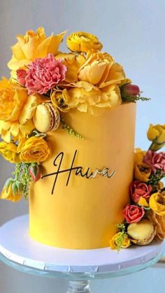 there is a yellow cake with flowers on the top and name written on the side