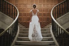 a woman in a wedding dress is standing on the stairs with her back to the camera