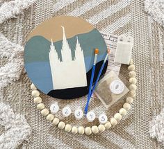 a table topped with beads and other items on top of a cloth covered floor next to a wooden bead necklace