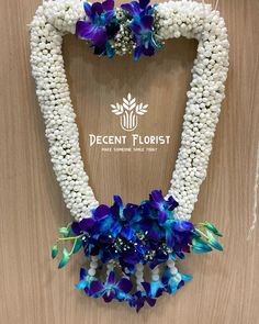 the blue and white flowers are arranged in a heart shaped frame with pearls on it