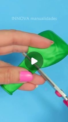 a person is using scissors to cut out the top of a piece of green material