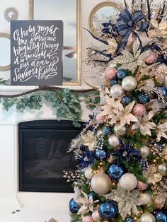 a decorated christmas tree in front of a fireplace with blue and white ornaments on it