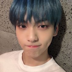 a young man with blue hair wearing a white t - shirt and looking at the camera