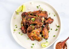 a white plate topped with wings covered in sauce and garnish