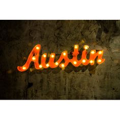 an illuminated neon sign that says austin on the side of a wall with lights