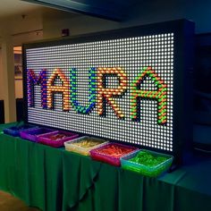 the mardi gras sign is lit up with colorful beads and plastic containers on it