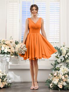 a woman in an orange dress standing next to flowers