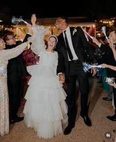 a bride and groom walking through confetti filled streets at their wedding reception in the evening