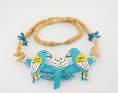 two birds are sitting on top of a beaded necklace with beads and wood beads