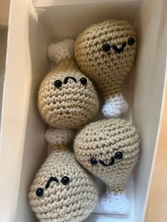 three crocheted balls with faces in a box