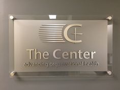 the center logo is displayed on a glass sign in front of a gray and white wall