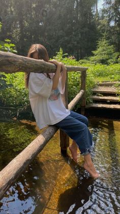 a woman is sitting on a log in the water