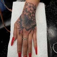 a woman's hand with red nails and a butterfly tattoo on her left wrist