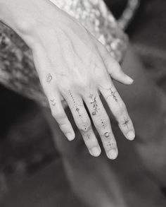 a woman's hand with stars and moon tattoos on her left thumb, while the other hand is in black and white