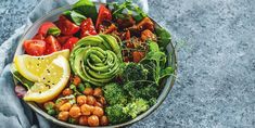 a bowl filled with lots of different types of vegetables and fruits on top of a table