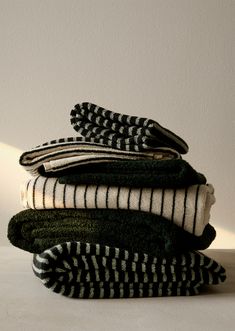 stack of folded towels sitting on top of each other in front of a white wall