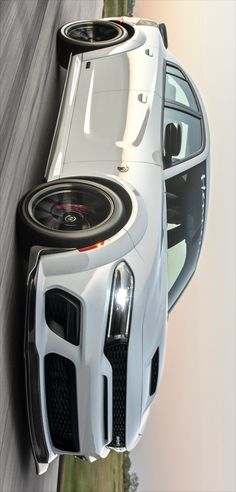 the front end of a white sports car with speakers on it's grilles