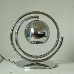 a metal object with a mirror on it's side sitting on a white surface