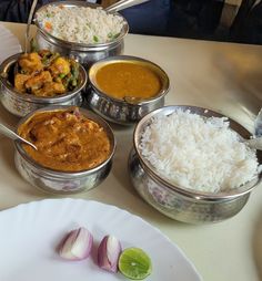 a table topped with bowls filled with different types of food next to rice and vegetables