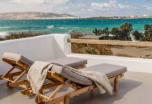 two lounge chairs sitting on top of a white roof next to the ocean and beach