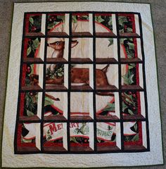 a quilted wall hanging with a deer and holly wreaths on it's sides